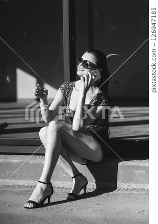 A young woman sits on the stairs and talks on the phone 126947181