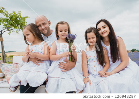 A happy mother and father gently embrace their daughters 126948287