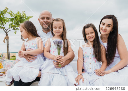 A happy family sits in the middle of a charming flower field 126948288