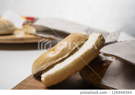 Closeup view of slice of bagel breads from brown paper bag on wooden board on a white background 126948564