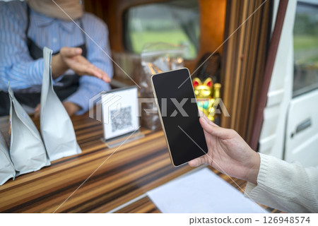 Female barista showing qr code to woman to scan with cellphone for payment. Mockup or copy space. Small business of coffee shop or cafe on truck 126948574