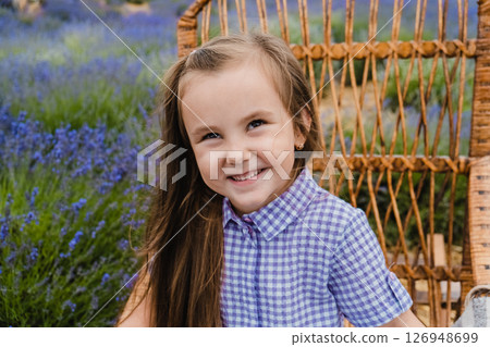 The girl is sitting in a rocking chair among the lavender 126948699
