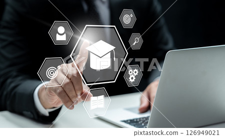Businessman using a laptop while touching the graduation cap icon. Technology innovation on a virtual screen. Concept of E-learning education Businessman using a laptop while touching the graduation cap icon. Technology innovation on a virtual screen. Concept of E-learning education 126949021