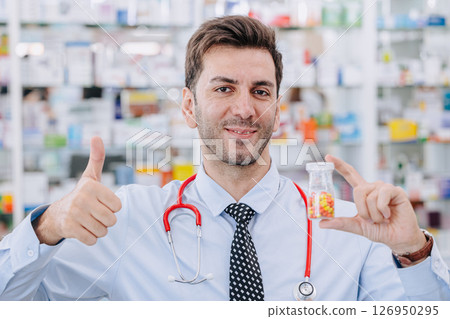 Happy Doctor Pharmacist man in drug store hand holding medicine capsule pills pack, Thumbs up Happy Doctor Pharmacist man in drug store hand holding medicine capsule pills pack, Thumbs up 126950295