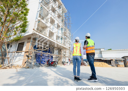 back view construction Engineer, architect working together at construction site. construction worker planning at construction site. back view construction Engineer, architect working together at construction site. construction worker planning at construction site. 126950303
