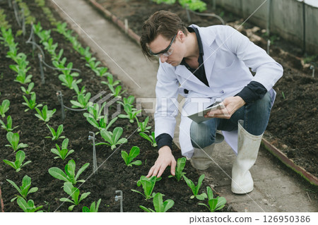 Modern farmer working plant research in organic farm. Biologist study collecting plant grow data Modern farmer working plant research in organic farm. Biologist study collecting plant grow data 126950386