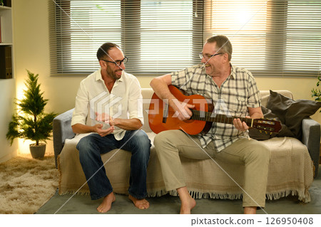 Father and adult son bonding over music, enjoying quality time with acoustic guitar. Father day concept Father and adult son bonding over music, enjoying quality time with acoustic guitar. Father day concept 126950408