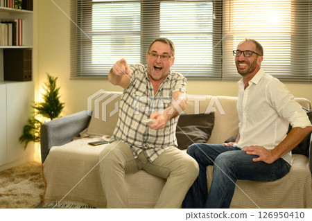 Happy father and son sitting on the couch enjoying a TV show together at home. Father day concept 126950410