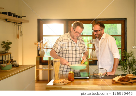 Smiling father and adult son preparing a pasta meal together in a cozy home kitchen. Father day concept 126950445