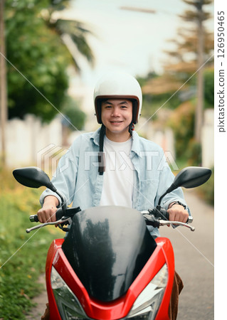 Portrait of a cheerful male motorcyclist ready to ride, captured in a suburban neighborhood Portrait of a cheerful male motorcyclist ready to ride, captured in a suburban neighborhood 126950465
