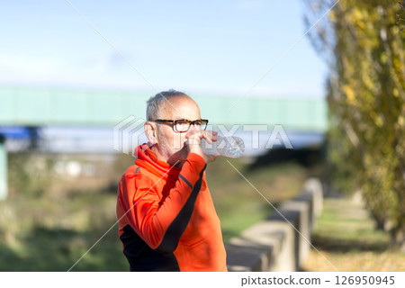 Senior man drinking water after outdoor exercise in nature 126950945