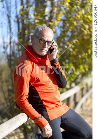 Senior man in sportswear talking on phone outdoors 126950947