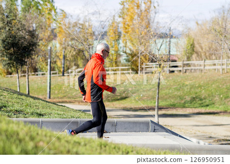 Senior man running up stairs in an outdoor park setting 126950951