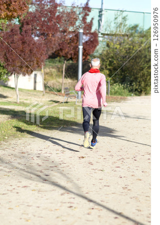 Senior man jogging in the park on a sunny day Senior man jogging in the park on a sunny day 126950976