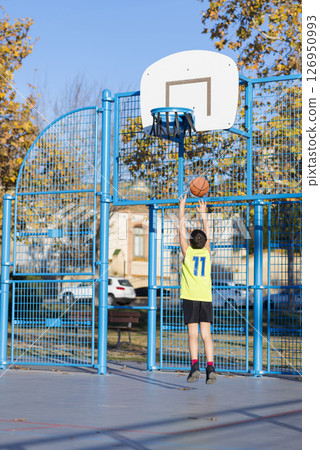 Young boy playing basketball outdoors on a sunny day. 126950993
