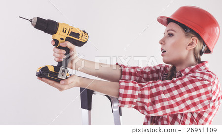 Woman using drill on ladder 126951109