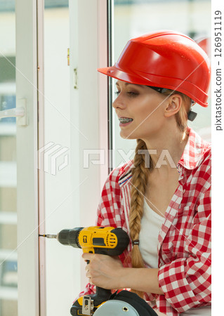 Woman using drill on window Woman using drill on window 126951119