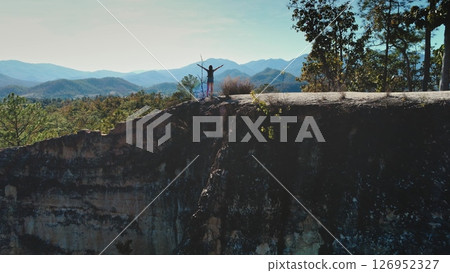 Tourist standing with open arms on a cliff at Pai Canyon, soaking in the stunning views of mountains and valleys in Chiang Mai Province, Thailand 126952327