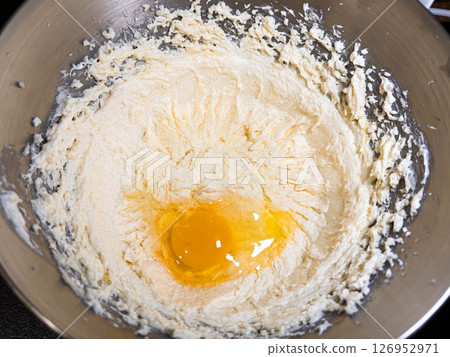 Beating butter, sugar and eggs in a grey metal bowl. The process of making cake and cookies by mixing butter, eggs and sugar. Beating butter, sugar and eggs in a grey metal bowl. The process of making cake and cookies by mixing butter, eggs and sugar. 126952971