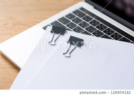 Documents and a computer clipped together 126954182