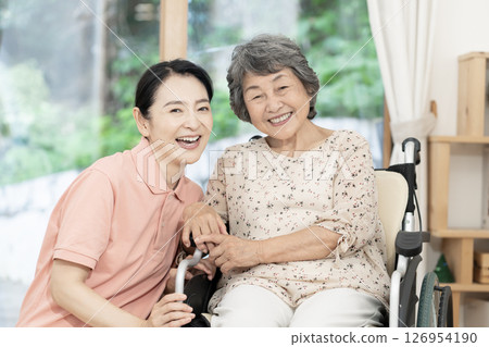 Caregiver caring for a senior woman sitting in a wheelchair Caregiver caring for a senior woman sitting in a wheelchair 126954190