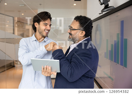 Young 30s and mature 45s teammates sharing fist bump gesture 126954382