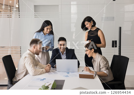 Joyful team gathered around laptop in conference room Joyful team gathered around laptop in conference room 126954434