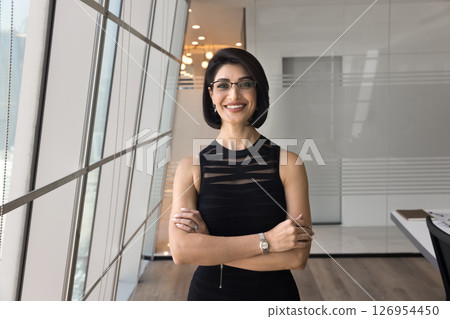 Beautiful businesswoman dressed in black dress standing in modern office 126954450