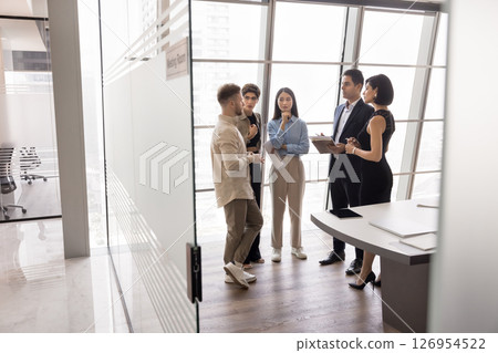 Group of professionals lead conversation standing in modern boardroom 126954522