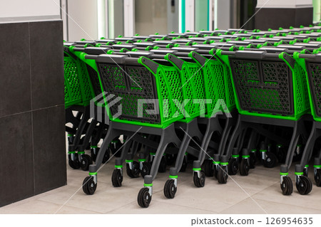 A row of clean green and black shopping carts arranged in a store A row of clean green and black shopping carts arranged in a store 126954635