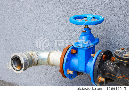 A blue valve is firmly attached to a sturdy metal pipe structure 126954645