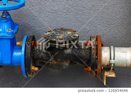 A blue valve is securely connected to a durable black pipe 126954646