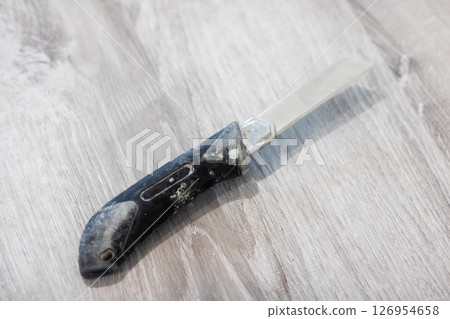 A Closeup of a Unique Folding Knife Displayed Elegantly on a Rustic Wooden Surface A Closeup of a Unique Folding Knife Displayed Elegantly on a Rustic Wooden Surface 126954658