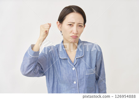 Woman in pajamas clenching her fist and getting angry on white background 126954888