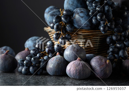 Blue grapes, blue plums, and figs on a black stone table. Blue grapes, blue plums, and figs on a black stone table. 126955037