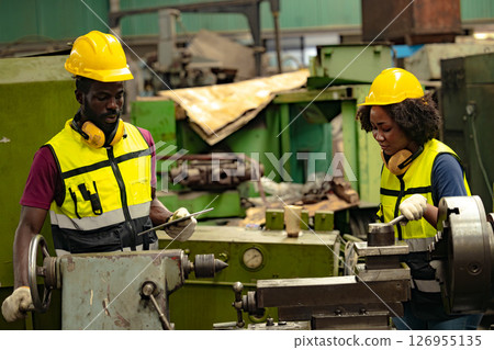 African black man professional technician engineer people workers in heavy industry training control operate CNC machine to young women 126955135