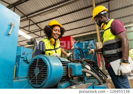 professional engineer worker male help assisting young women worker to check service old machine in heavy industry plant 126955136