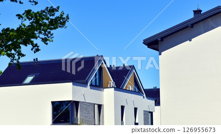 Residential homes with modern facade. Terraced family homes in newly developed housing estate. The real estate market in the suburbs. New single family houses in a new development area.  126955673