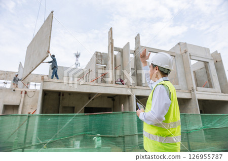 Concrete precast building, Construction engineer foreman working at construction site control operated precast wall placement 126955787
