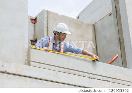 Home builder worker using tape measurement working in house building construction site 126955802