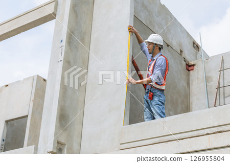 Home builder worker using tape measurement working in house building construction site 126955804