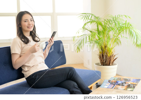 一位女士一邊喝咖啡一邊看著她的智慧型手機 126956523