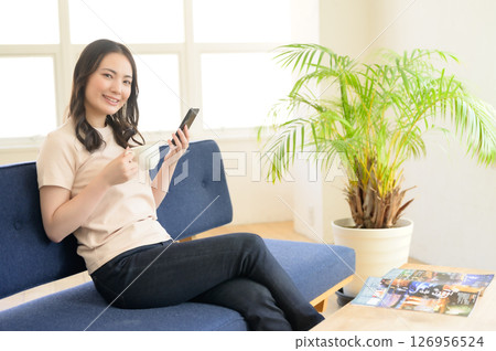 A woman looking at her smartphone while holding a cup of coffee 126956524