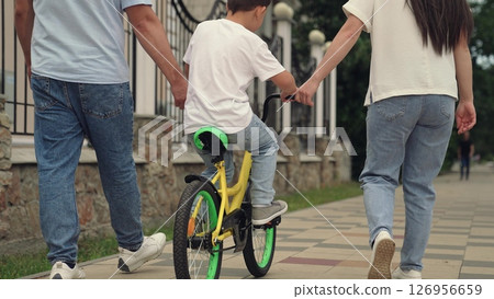 family enjoying adventure running, adults running helping baby ride bike, mother father, boy laugh smile face, smile child face, happy father and mother running teaching little son to ride bike 126956659