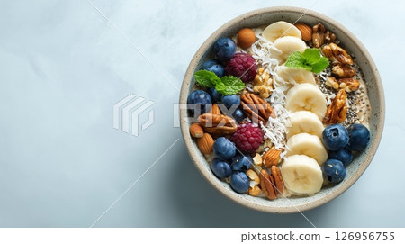 Healthy eating idea with bright oatmeal decorated with berries and nut toppings, background with copy space 126956755