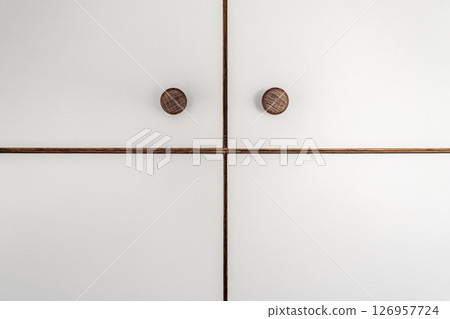 White cabinet doors of wooden closet with wooden knobs close-up as modern design backdrop White cabinet doors of wooden closet with wooden knobs close-up as modern design backdrop 126957724