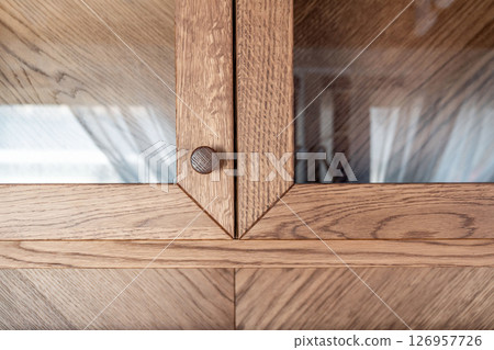 Elegant oak cabinet featuring glass doors and wooden knobs close view Elegant oak cabinet featuring glass doors and wooden knobs close view 126957726