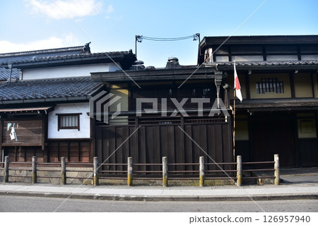 Old townscape of Takayama City, Gifu Prefecture, Japan. Old houses with the Japanese flag flying and beautiful blue sky 126957940