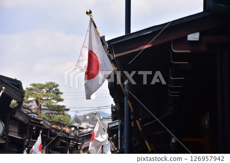 日本岐阜縣高山市的古老城鎮景觀。古老的房屋上飄揚著日本國旗,藍天白雲 日本岐阜縣高山市的古老城鎮景觀。古老的房屋上飄揚著日本國旗,藍天白雲 126957942