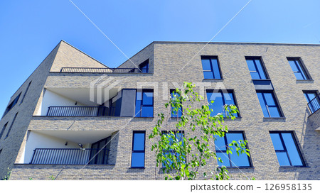 Eco architecture. Green tree and new residential building. Harmony of nature and modernity. Modern apartment building with new apartments in a green residential area. Eco architecture. Green tree and new residential building. Harmony of nature and modernity. Modern apartment building with new apartments in a green residential area. 126958135